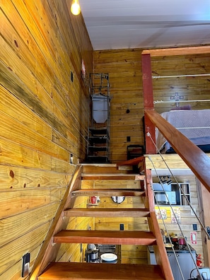 A wooden interior with a staircase leading to a kitchen area. - Casa de Praia (Buzios)