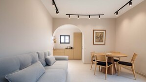 Un salon moderne avec un canapé, une table à manger et des chaises, et un coin cuisine à l’arrière-plan.
