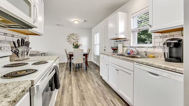 A modern kitchen with white cabinets, a built-in oven, and a coffee maker.
