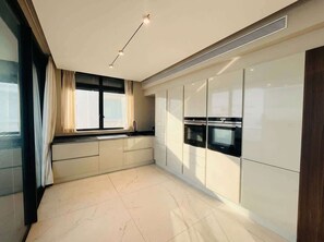 Una cocina moderna con armarios blancos, una ventana con cortinas y piso de baldosas.