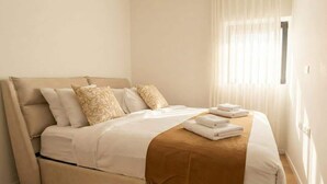 A neatly made bed with a beige headboard and pillows, a brown blanket, and folded towels on the side. - #SeaView Beach Front 3BR TLV  | By SweetyGuest (Tel Aviv-Yafo)