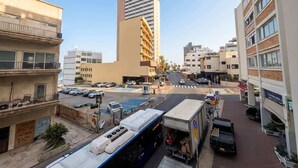 A city street with buildings, parked cars, and a bus. - #SeaView Beach Front 3BR TLV  | By SweetyGuest (Tel Aviv-Yafo)