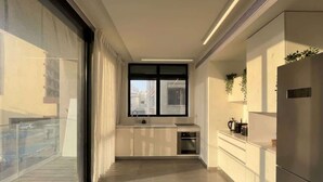 A modern kitchen with a large window, a built-in oven, and a refrigerator. - #SeaView Beach Front 3BR TLV  | By SweetyGuest (Tel Aviv-Yafo)