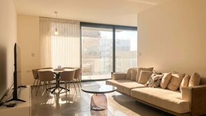 A modern living room with a sofa, a round coffee table, and a dining area with chairs and a table. - #SeaView Beach Front 3BR TLV  | By SweetyGuest (Tel Aviv-Yafo)