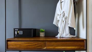 A compact, modern room with a wooden desk, a small potted plant, a towel, and an iron.