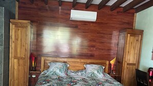 Een houten bed met een bloemenprint sprei, een houten hoofdbord en een bank aan het voeteneinde.