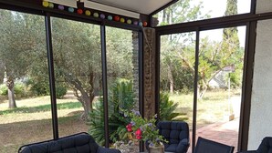 A covered patio with a round table and four black cushioned chairs. - Large villa with 11x5m pool in 7700 M2 grounds. Veranda and multiple terraces. (Montescot)