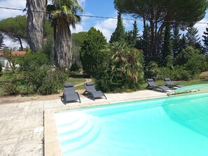 Un espace piscine doté de chaises longues et d’une piscine à l’eau d’un bleu cristallin.