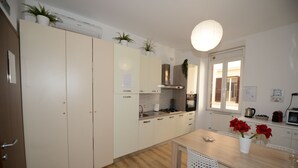 A modern kitchen with white cabinets, a wooden countertop, and a dining area with a table and chairs.