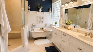 A bathroom with a freestanding bathtub, a large mirror, and a walk-in shower.