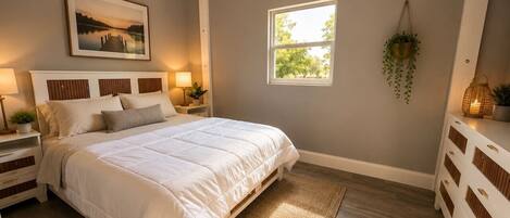 A bedroom with a bed, bedside tables, a window, and a wall-mounted plant.
