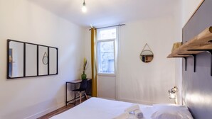 Ein Hotelzimmer mit Bett, Schreibtisch, Stuhl, Fenster und Spiegel an der Wand.