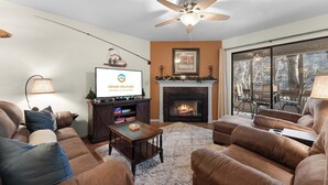 A living room with a fireplace, sofa, and television. - Water's Edge Hideaway – 6ppl (Branson)