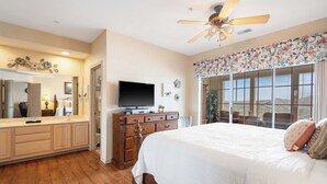 A bedroom with a bed, dresser, TV, and a ceiling fan. - Golf View Getaway – For 6 (Branson)