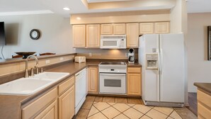 A modern kitchen with a built-in microwave, oven, and refrigerator, wooden cabinets, and a tiled floor. - Golf View Getaway – For 6 (Branson)