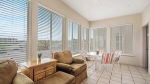 A spacious room with large windows, a sofa, a dining table with chairs, and a ceiling fan. - Golf View Getaway – For 6 (Branson)