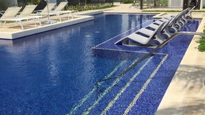 Une piscine avec des chaises longues et un espace de détente abrité.