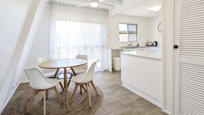 Una cocina moderna con una isla central, un comedor con una mesa redonda y sillas, y un ventilador de techo.