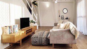 Una sala de estar moderna con un sofá, un televisor y una mesa consola de madera con libros.