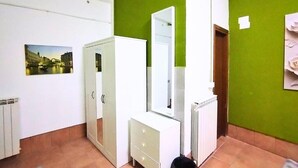 Een kamer met een witte garderobe, een spiegel, een radiator en een groene wand.