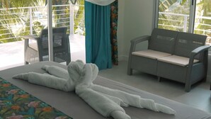 Une pièce comprenant un lit, un canapé et un fauteuil. La fenêtre donne sur un paysage verdoyant.