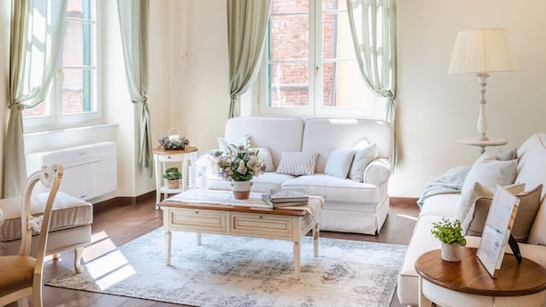 A spacious living room with a chandelier, a white sofa, a coffee table, and a side table with a lamp. - Bright and Central Apartment in Lucca (Lucca)