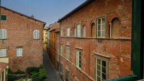 A narrow alleyway between buildings with red brick facades, featuring arched windows and a green door on the right. - Bright and Central Apartment in Lucca (Lucca)