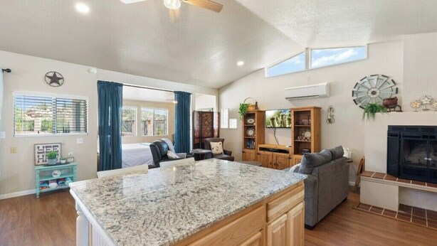 A spacious living area with a large kitchen island, a fireplace, and a ceiling fan. - Private Guesthouse w/ Pool in Historic Wickenburg! (Wickenburg)