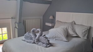 Une chambre à coucher avec un lit, deux tables de chevet avec des lampes, un radiateur et une fenêtre donnant sur un paysage verdoyant.