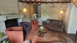 Un salon chaleureux avec une cheminée, des murs en pierre et des poutres en bois rustiques.