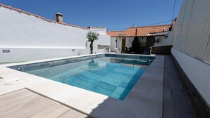 Une piscine rectangulaire à l’eau d’un bleu limpide, entourée d’une terrasse aux couleurs claires.