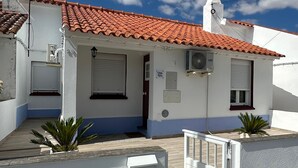 Un immeuble résidentiel avec un toit en tuiles, une façade blanche et une entrée fermée par un portail.