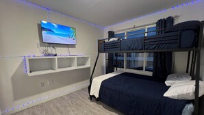 A room with bunk beds, a mounted TV, and shelves. - Delightful 3-bedroom house with Sunset views (Homestead)