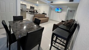 A compact living space with a dining area, kitchenette, and a TV mounted on the wall. - Delightful 3-bedroom house with Sunset views (Homestead)
