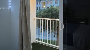 A balcony with a sliding glass door, a white railing, and a string of lights along the ceiling. - Delightful 3-bedroom house with Sunset views (Homestead)