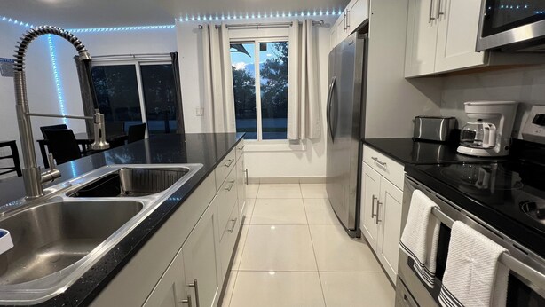 A modern kitchen with a large island, stainless steel appliances, and a view to the outdoors. - Delightful 3-bedroom house with Sunset views (Homestead)
