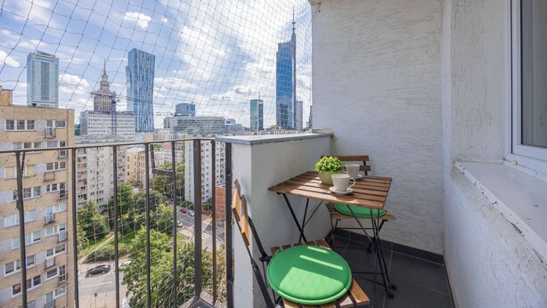 A balcony with a view of a cityscape, a small table with a plant, and a chair. - Stylish Apartment in the Center | Balcony | Workspace (Warszawa)