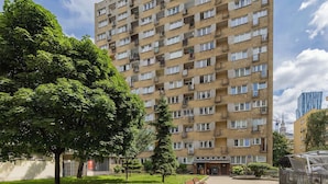 A multi-story residential building with balconies, a courtyard with benches, and a small garden area. - Stylish Apartment in the Center | Balcony | Workspace (Warszawa)