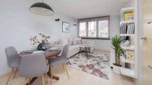 A modern apartment with a dining area, a sofa, a bookshelf, and a potted plant. - Stylish Apartment in the Center | Balcony | Workspace (Warszawa)