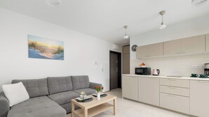 A modern living room with a grey sofa, a wooden coffee table, and a painting of a sunset on the wall.