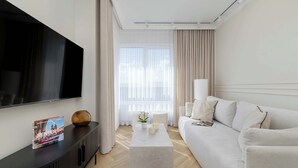 Ein modernes Wohnzimmer mit einem Flachbildfernseher, einer Couch, einem Couchtisch und einer Zeitschrift auf dem Couchtisch.