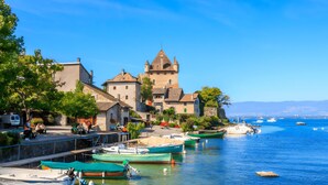 Une ville côtière dotée d’une tour historique, de bateaux amarrés le long du port et d’un ciel bleu azur.