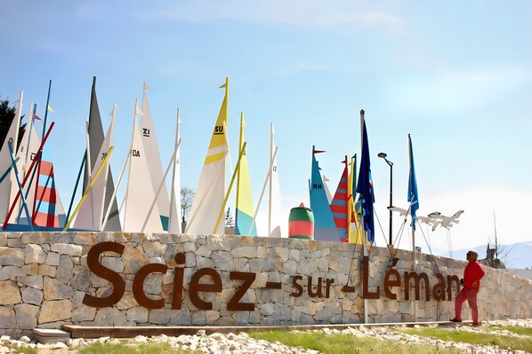 A stone wall with the text 'Sciez-sur-Lemans' and a row of colorful sailboats.
