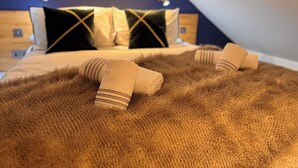 Quarto com teto inclinado, cama com duas almofadas e um tapete marrom fofinho.