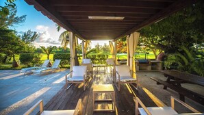 Een overdekt terras met loungezetels en tafels, een zwembad en uitzicht op een golfbaan.