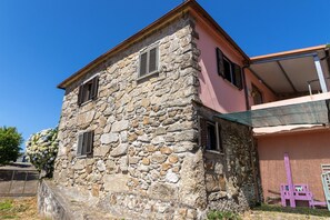 Un edificio de piedra con dos ventanas y una pared rosa.