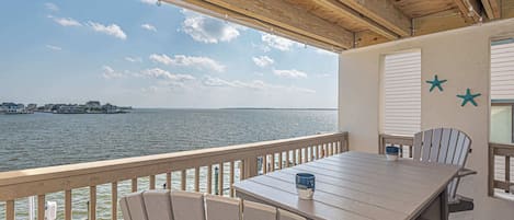 A wooden deck with a table and chairs overlooking a body of water.