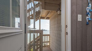 Een houten terras leidt naar een balkon met uitzicht op het water.