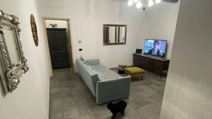 Un salon avec un canapé, un téléviseur et une petite table.