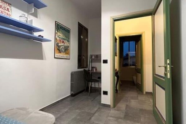 Un pasillo estrecho con un radiador, una silla y un cartel en la pared.